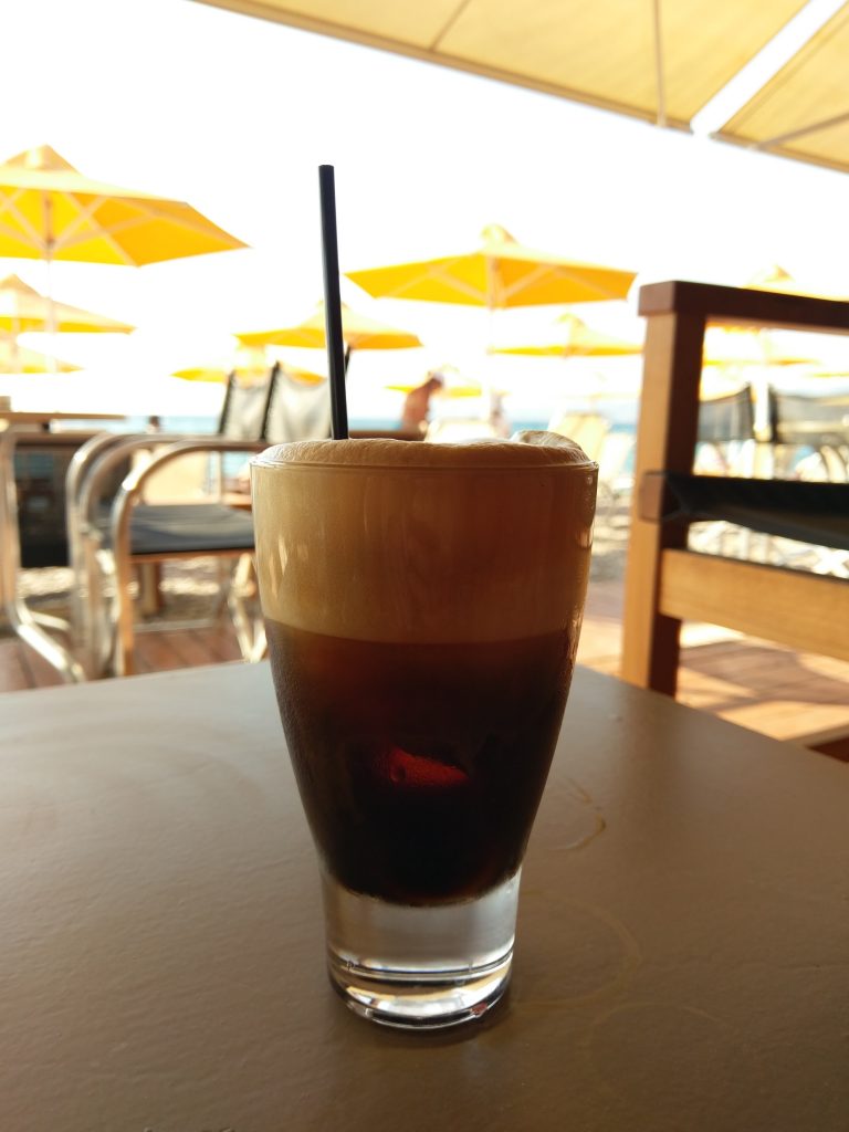 Pause am Strand mit dem Lieblingsgetränk der Griechen - eisgekühlter Café Crema